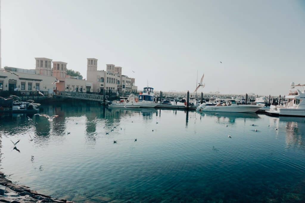 Buildings and boats stand in a harbour at Jumeirah Fishing Harbour Dubai
