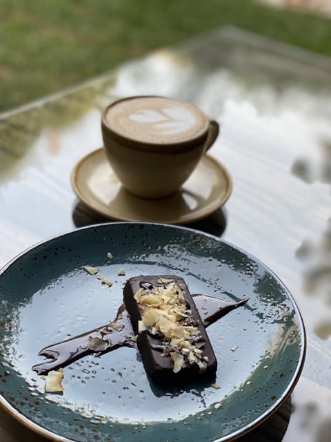 Chocolate fudge bar on a plate next to cup of coffee