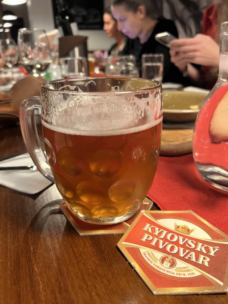A glass of beer on a table next to a coaster that says Kyjovský pivovar