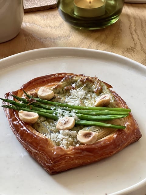 An asparagus and green cream and hazelnut topped Danish pastry