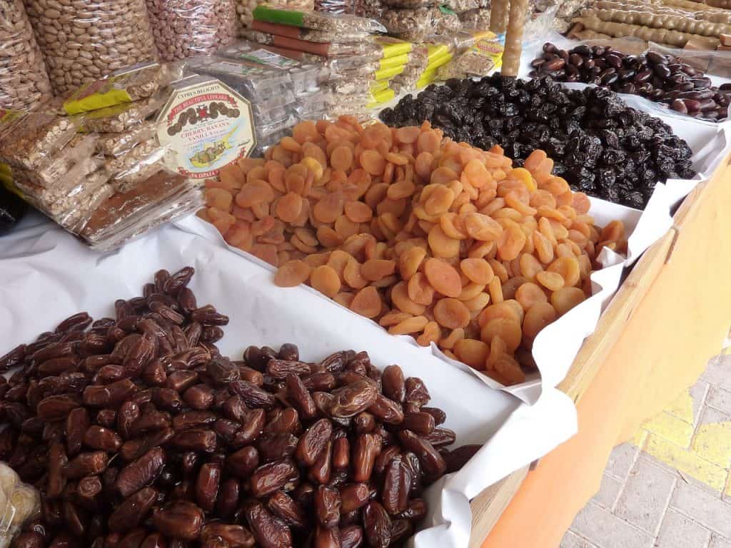 Dried apricots and dates in a market, side by side, displayed for sale