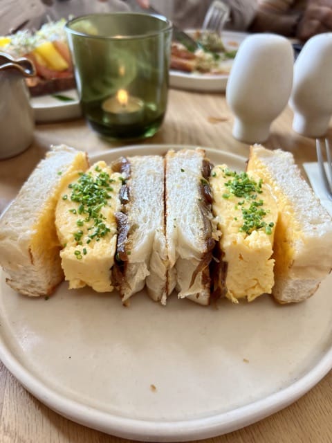 A sandwich of a French omelet and caramelized onions in white bread cut into two.