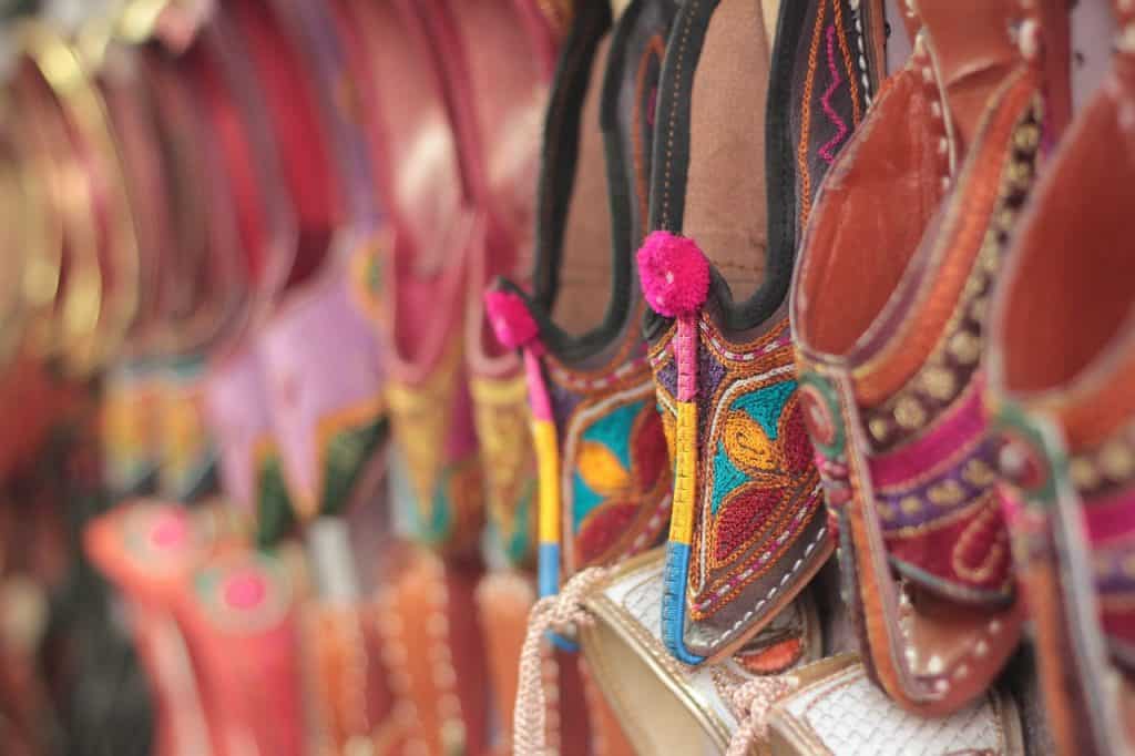 Colorful embroidered flat shoes hang on a display 